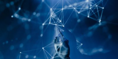 Mão robótica alcança uma rede digital azul, simbolizando o uso de inteligência artificial e sistemas automatizados.