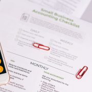 Checklist e calculadora sobre uma mesa, representando o controle financeiro de um pequeno negócio.