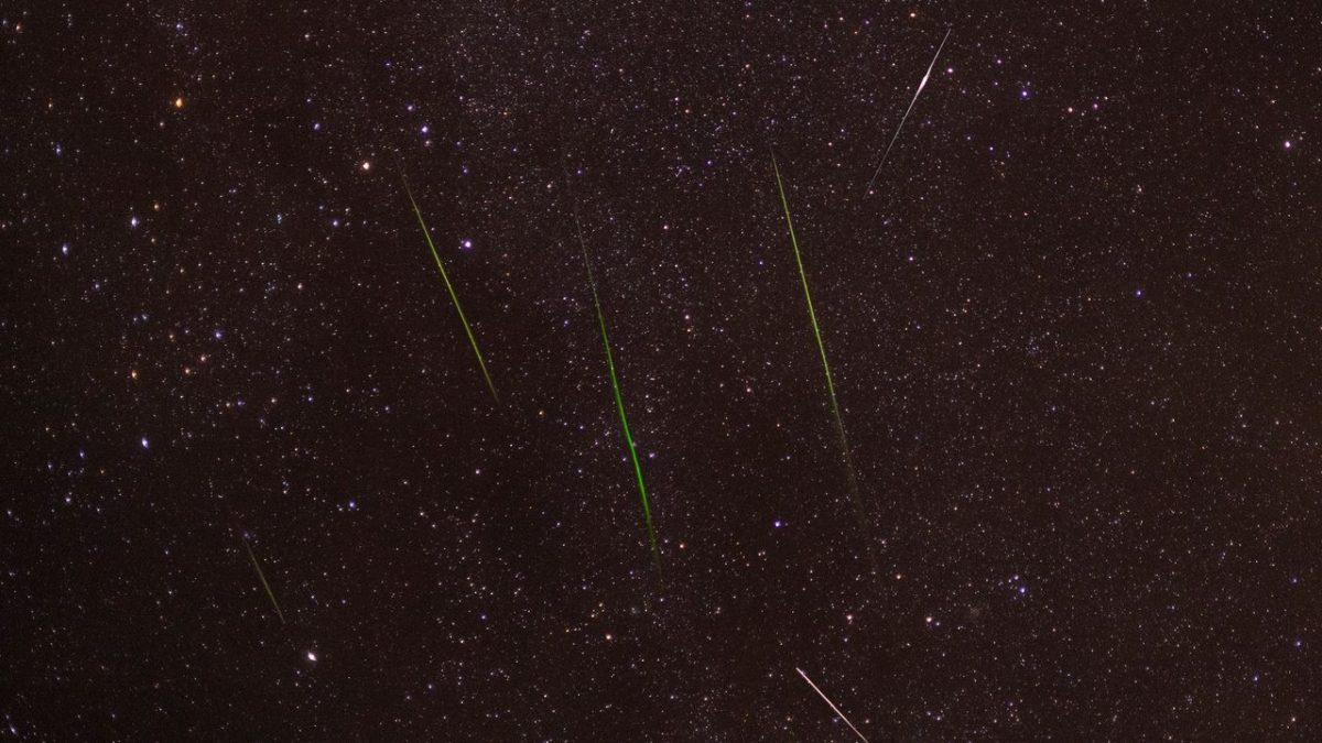 Meteoros luminosos cruzam um céu noturno repleto de estrelas durante uma chuva de meteoros.