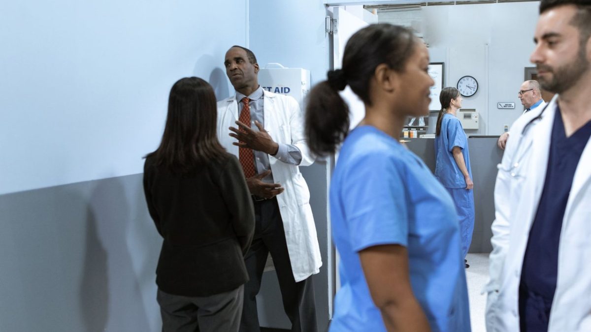 Médicos e enfermeiros conversam e analisam informações em um ambiente hospitalar.