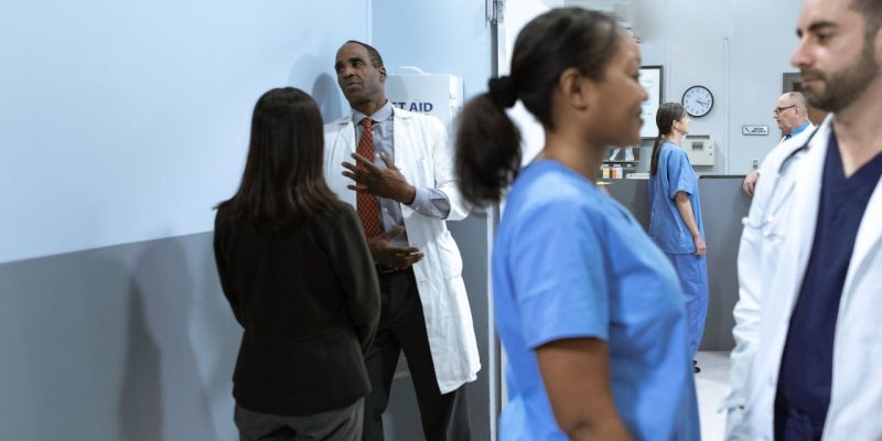 Médicos e enfermeiros conversam e analisam informações em um ambiente hospitalar.