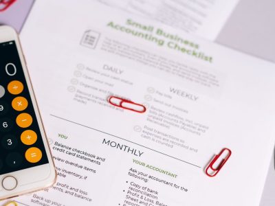 Checklist e calculadora sobre uma mesa, representando o controle financeiro de um pequeno negócio.