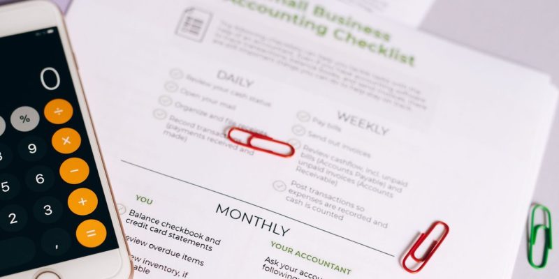 Checklist e calculadora sobre uma mesa, representando o controle financeiro de um pequeno negócio.