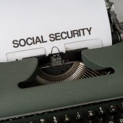 Máquina de escrever com referência à seguridade social, acompanhada de elementos que remetem a benefícios públicos e apoio econômico.